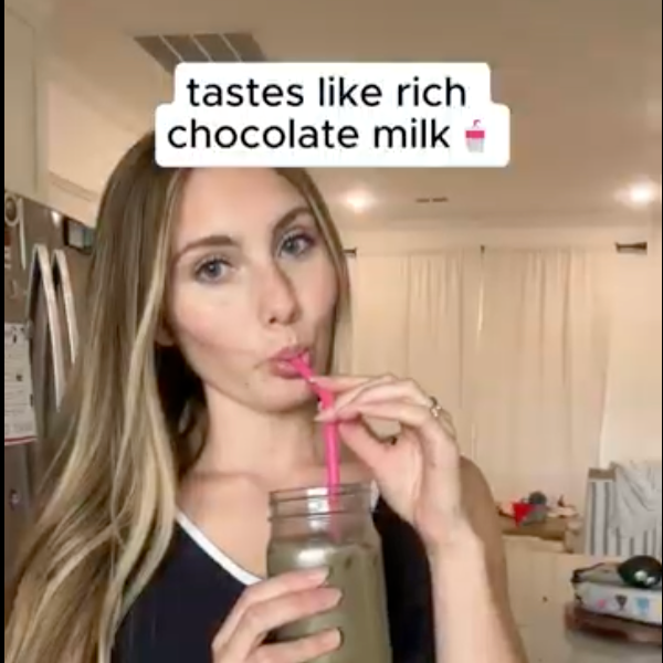 Woman drinking a chocolate milkshake with text overlay in a kitchen.