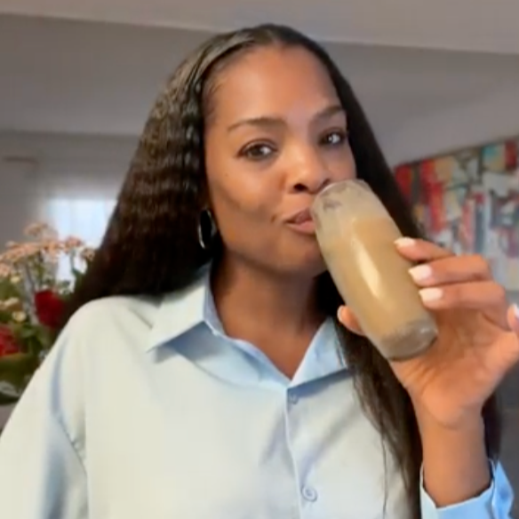 Woman drinking from a glass bottle indoors